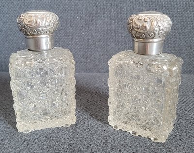 A pair of large antique crystal perfume bottles with silver lids