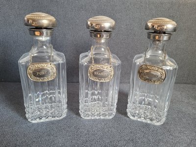 Vintage set of crystal decanters with silver-plated necks, silver-plated lids and silver-plated tags/labels.