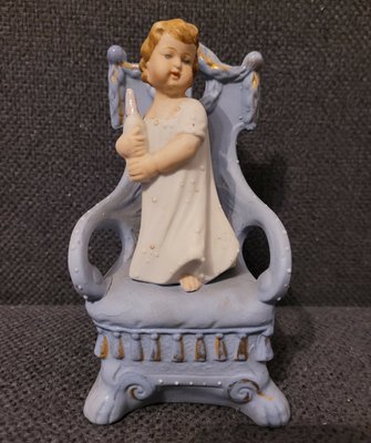 An old German porcelain statuette of a girl standing on a chair