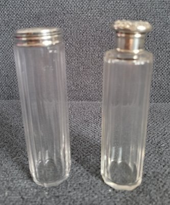 Two antique glass bottles with silver lids.