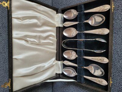 Vintage silver-plated coffee spoons and sugar tongs in an original case.